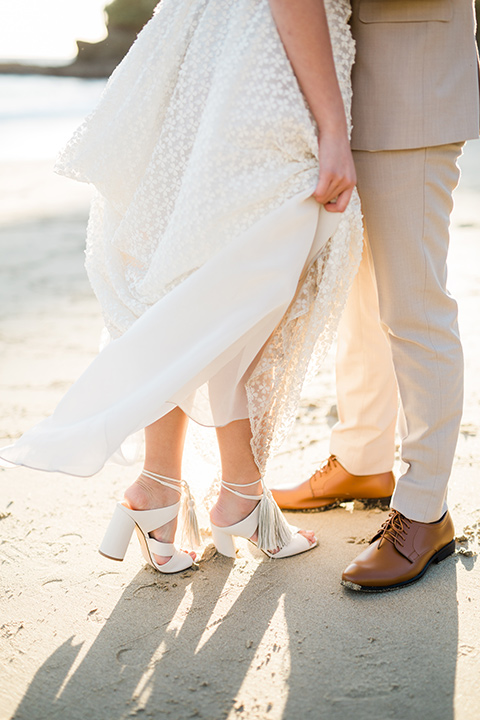  bride in a cream colored bohemian inspired gown with a gold crown, groom in a tan suit with a burgundy velvet bow tie, at the beach 