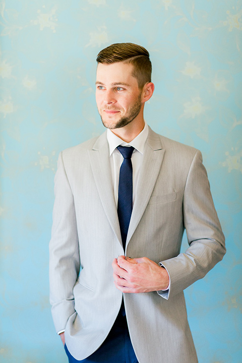  groom in a light grey suit coat with dark blue pants and a long tie 