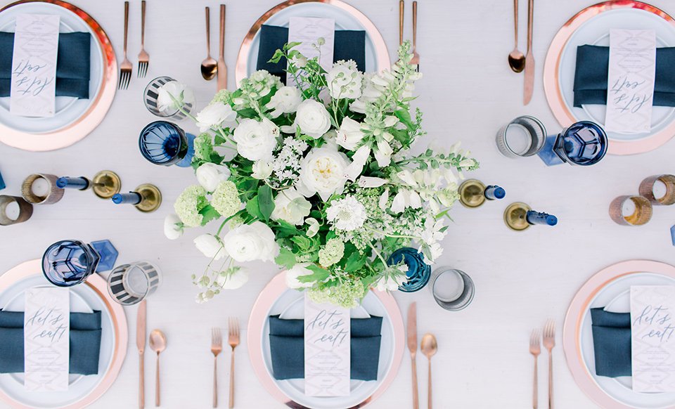 white table with white farmer chairs and blue and blush décor and flatware