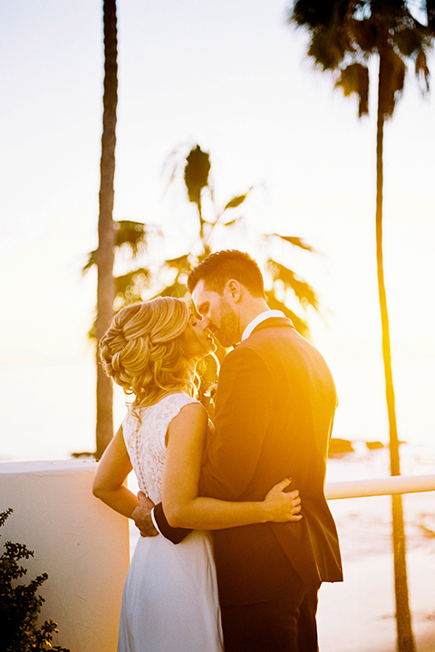 The-Inn-at-Laguna-Beach-bride-and-groom-at-sunset-bride-in-a-form-fitting-gown-with-a-high-slit-and-high-neckline-groom-in-a-grey-blue-suit-with-a-matching-bow-tie