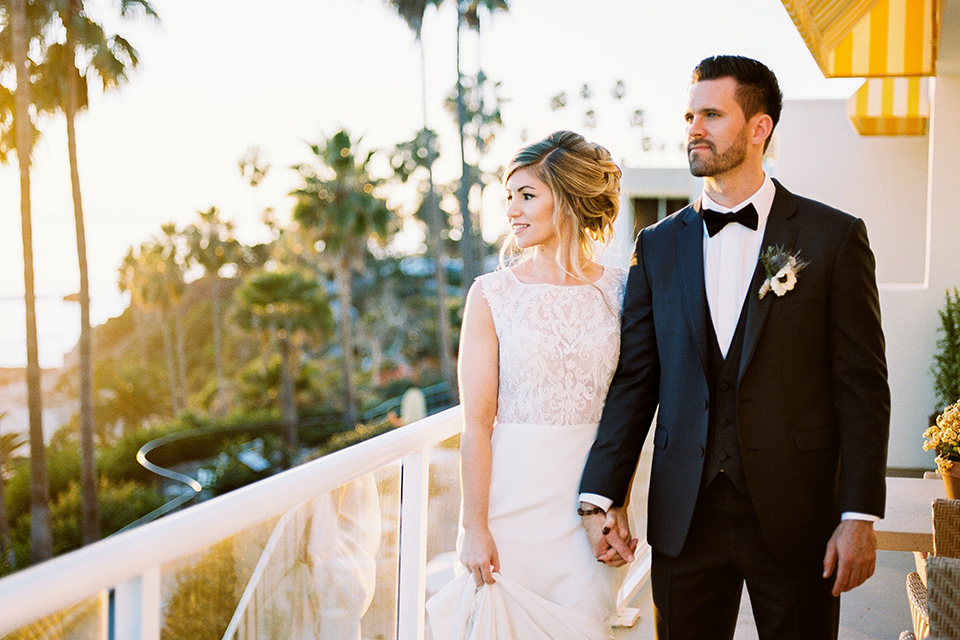 The-Inn-at-Laguna-Beach-bride-and-groom-walking-at-sunset-bride-wearing-a-white-silk-dress-with-a-high-neckline-groom-wearing-a-slate-bue-suit-with-matching-bow-tie