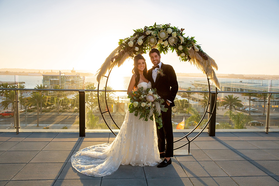 Intercontinental-elopement-shoot-bride-and-groom-at-ceremony-space-groom-in-velvet-tuxedo-with-black-ants-and-a-black-bow-tie-bride-in-a-flowing-gown-with-straps-and-lace