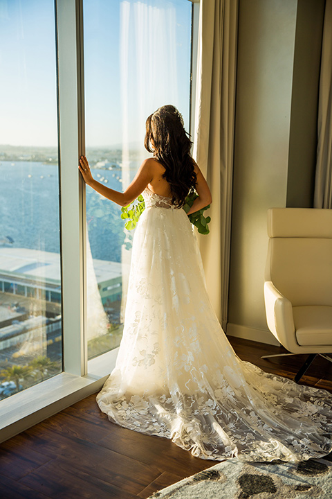 Intercontinental-elopement-shoot-bride-looking-out-the-window-bride-in-a-flowing-white-gown-with-lace