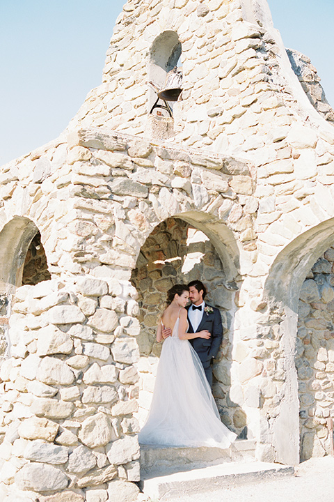 italian-style-wedding-bride-and-groom-in-bell-tower-bride-in-a-flowing-gown-with-straps-groom-in-a-grey-tuxedo-with-black-bow-tie