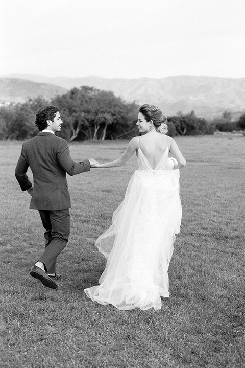 italian-style-wedding-bride-and-groom-walking-away-bride-in-a-flowing-gown-with-straps-groom-in-a-grey-tuxedo-with-black-bow-tie