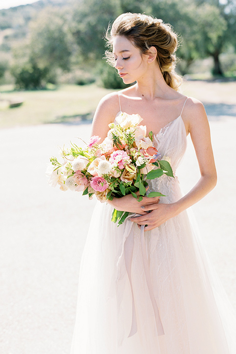 italian-style-wedding-bride-holding-flowers-in-a-flowing-gown-with-straps-and-her-hair-up