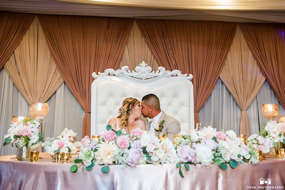 Bride and groom kiss at the sweetheart table during the wedding reception