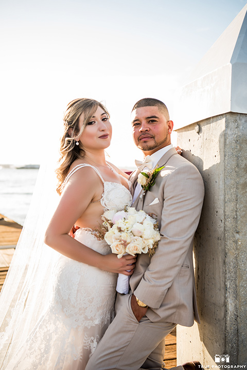 bride and groom looking at the camera and standing against concrete