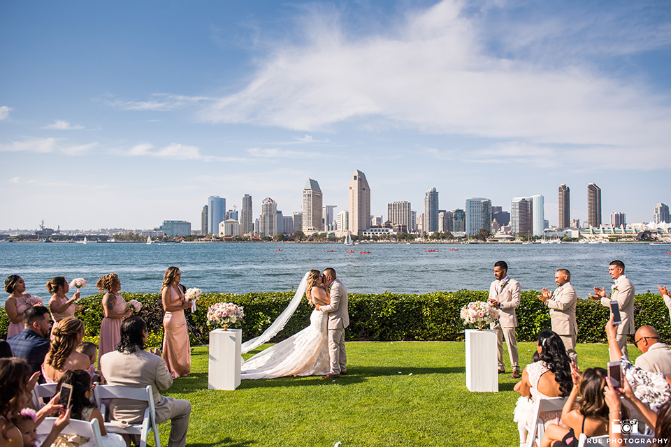 bride and groom kiss during wedding ceremony in front of downtown san diego skyline