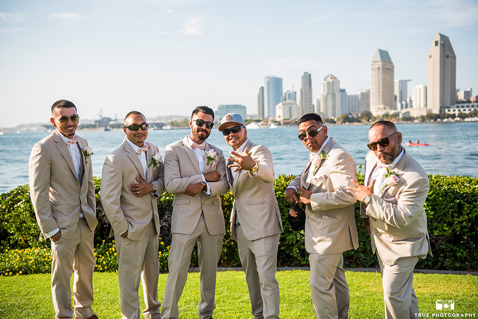 grooms and groomsmen pose in tan notch lapel suits and bow ties