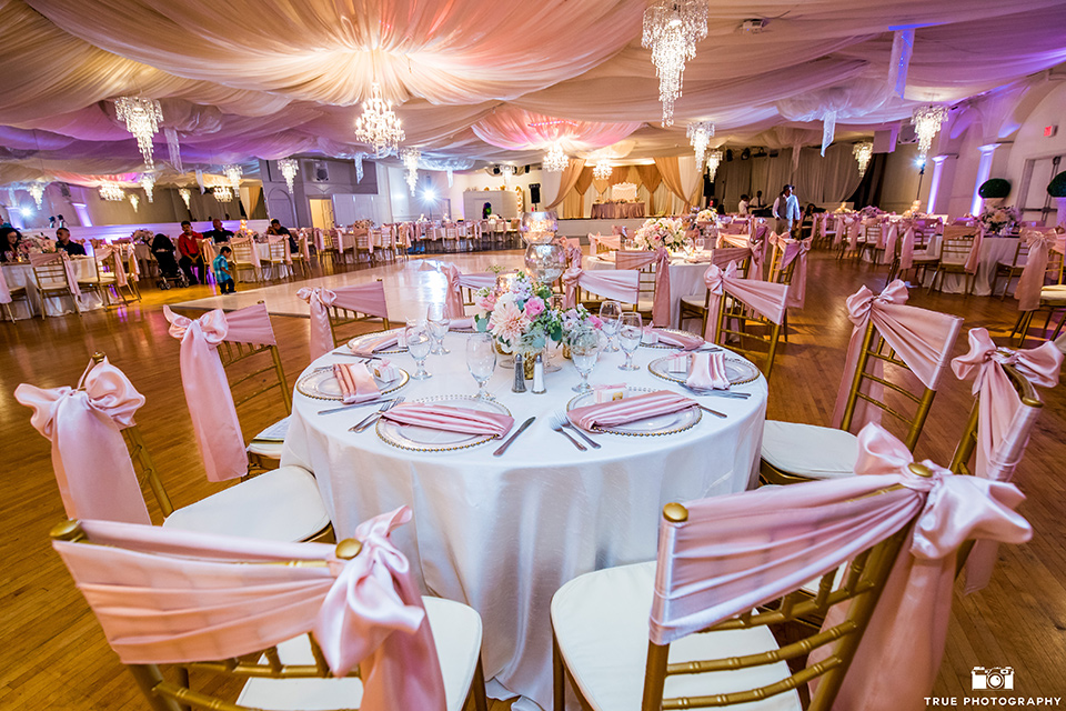 Fiesta Hall wedding reception space with white liners and pink ribbon details and gold flatware