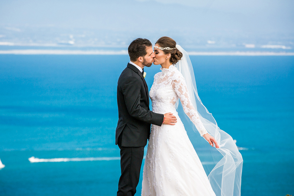 Admiral Kidd Club bride and groom with ocean bride in a lace and tulle gown with a high neckline and sleeves groom in a traditional black tuxedo