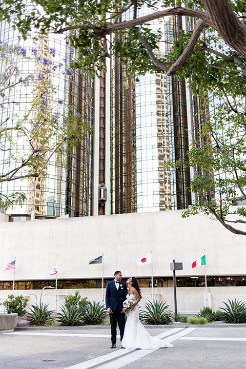 walt-disney-concert-hall-bride-and-groom-standing-outside-groom-in-a-navy-shawl-lapel-tuxedo-with-a-black-bow-tie-bride-in-a-white-strapless-gown-with-a-sweetheart-neckline