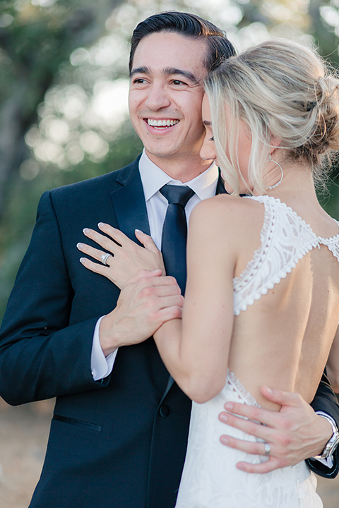 Arroyo-Grande-Wedding-couple-holding-each-other-bride-in-a-boho-style-gown-with-a-keyhole-back-and-high-neckline-and-fringe-white-the-groom-wore-a-traditional-black-tuxedo-and-black-long-tie