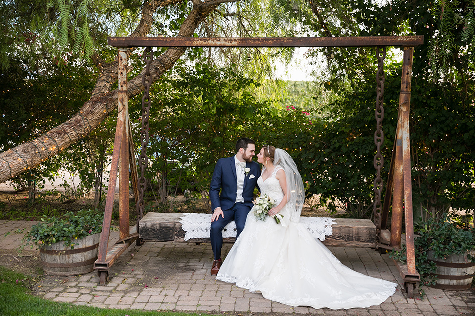 Villa de Amore wedding bride and groom on a swing with bride wearing a tulle ballgown with lace details and straps and the groom wearing a dark blue suit