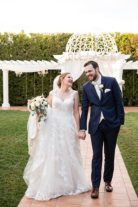 wedding bride and groom walking along brick path while holding hands