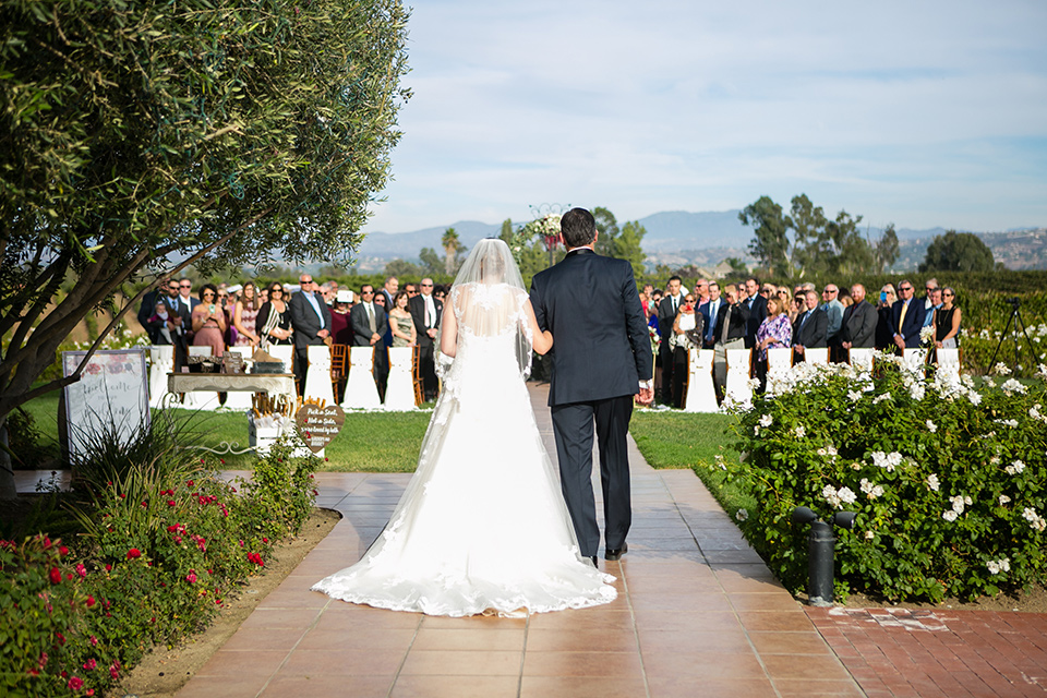 bride walking down the aisle while wearing a tulle ballgown with lace details and straps