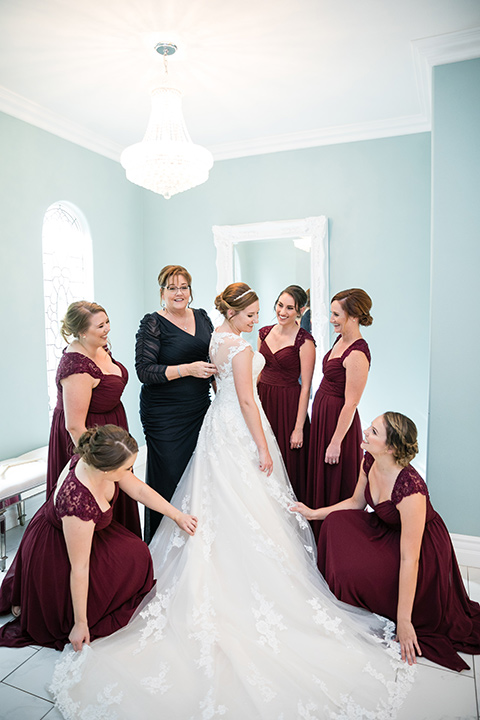 bridesmaids in burgundy dresses pose with bride in white gown 