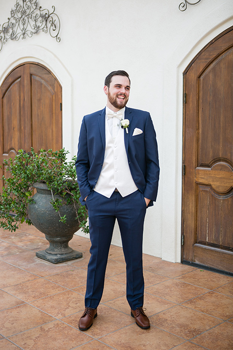 villa de amore wedding groom stands in front of venue with hands in pocket wearing a blue suit