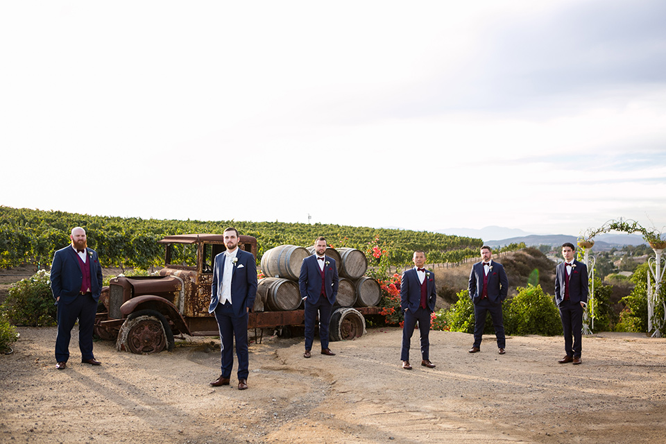 Groomsmen pose at temecula vineyard in front of rolling hills and vines