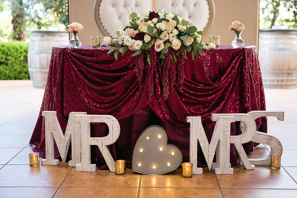 sweetheart table with letter blocks that say mr and mrs and a burgundy table cloth 