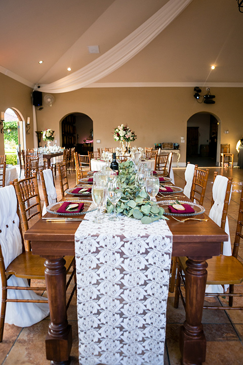 wedding tabe set up and decorations with white lace tablecloth and wooden chairs