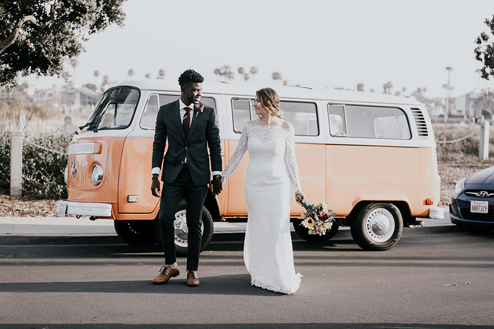 coronado-yacht-club-wedding-bride-and-groom-in-front-of-vw-bus-bride-in-a-lace-form-fitting-gown-groom-in-a-charcoal-grey-suit-with-red-tie