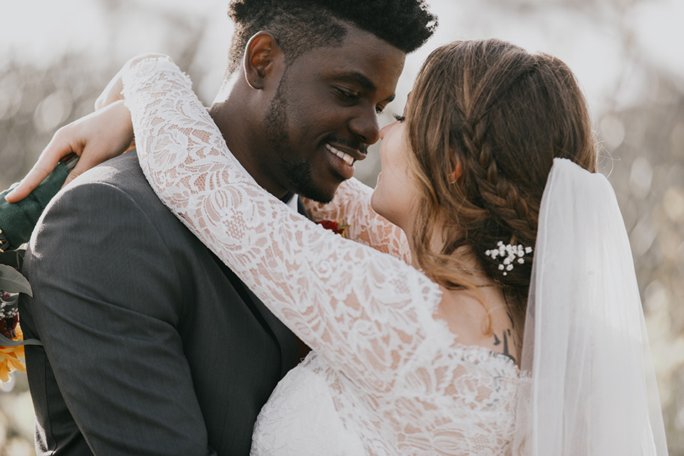 coronado-yacht-club-wedding-bride-and-groom-looking-at-eachother-bride-in-a-lace-form-fitting-gown-with-sleeves-groom-in-a-charcoal-grey-suit-with-red-tie