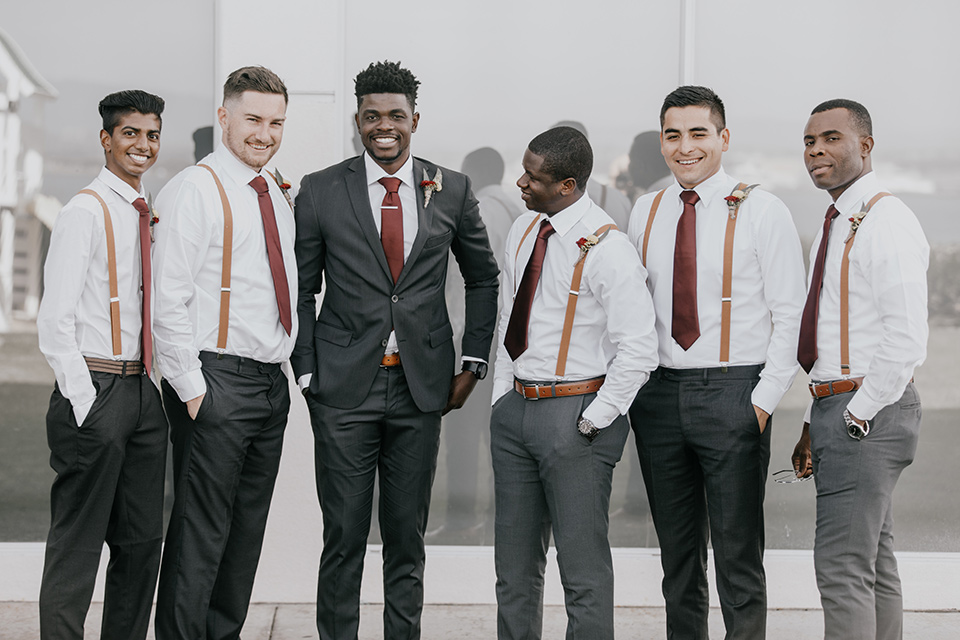 coronado-yacht-club-wedding-groom-and-groomsmen-groomsmen-in-a-casual-look-with-just-charcoal-pants-white-shirt-and-red-tie-groom-in-charcoal-suit-with-red-tie