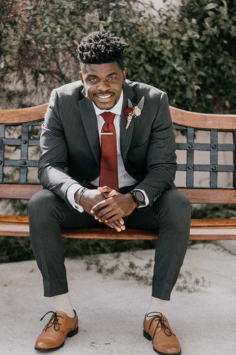 coronado-yacht-club-wedding-groom-sitting-groom-in-a-charcoal-grey-suit-and-deep-red-long-tie