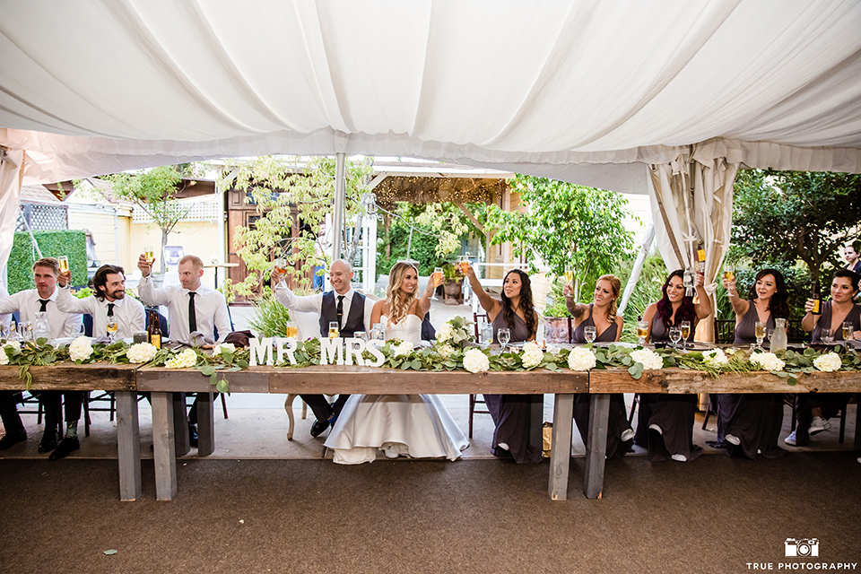 twin-oaks-weddings-bridal-party-at-dinner-bridesmaids-in-long-purple-dresses-with-different-necklines-groomsmen-in-grey-suits-bride-in-a-strapless-fit-and-flare-gown-with-a-sweetheart-neckline-groom-in-a-charcoal-grey-suit-with-black-long-tie