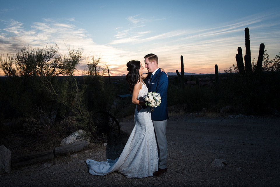 tanque-verde-ranch-arizona-wedding-bride-and-groom-at-sunset-the-bride-in-a-white-formfitting-gown-with-thin-straps-and-the-groom-and-in-grey-suit-pants-and-a-blue-suit-coat