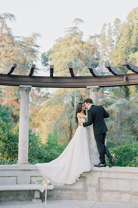 Kimberly-crest-house-shoot-bride-and-groom-kissing-standing-groom-in-a-traditional-black-tuxedo-with-white-shirt-and-black-bow-tie-bride-in-a-modern-princess-inspired-flowing-white-gown-with-a-full-skirt