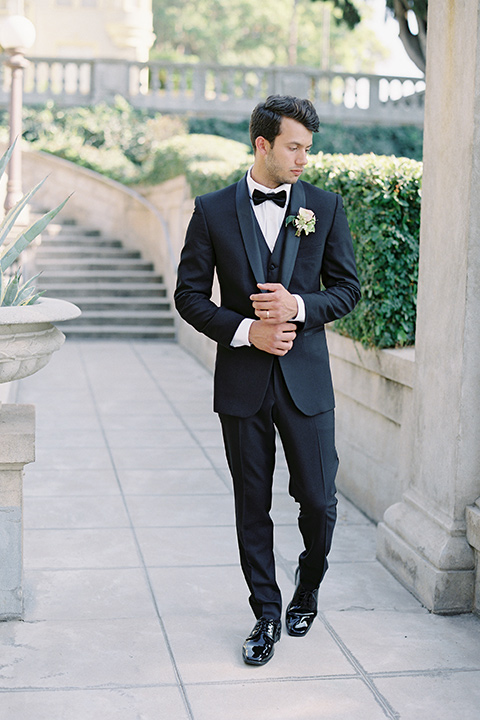 Kimberly-crest-house-shoot-groom-walking-in-a-traditional-black-tuxedo-with-white-shirt-and-black-bow-tie