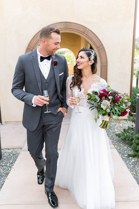 bride in a white lace gown with a full skirt and long lace sleeves and her hair in a finger wave and the groom in a charcoal tuxedo with a black bow tie