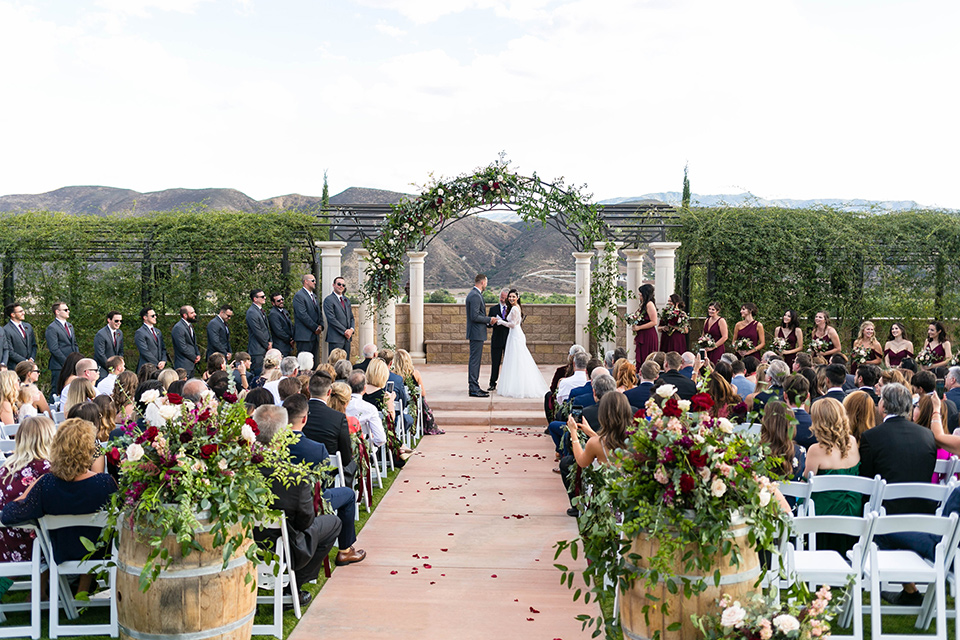  bride in a white lace gown with a full skirt and long lace sleeves and her hair in a finger wave and the groom in a charcoal tuxedo