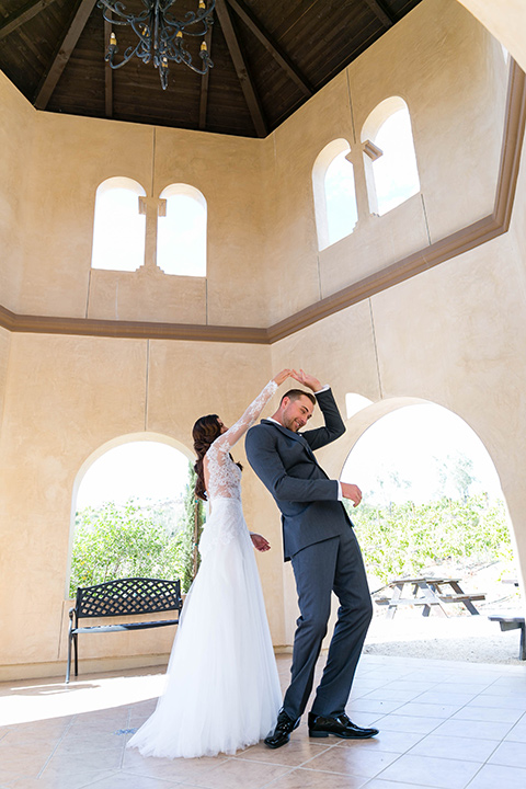  bride in a white lace gown with a full skirt and long lace sleeves and her hair in a finger wave and the groom in a charcoal tuxedo with a black bow tie 