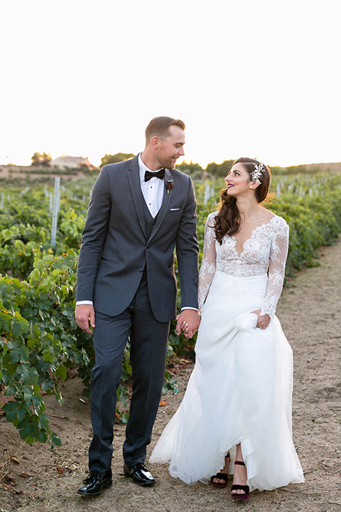 bride in a white lace gown with a full skirt and long lace sleeves and her hair in a finger wave and the groom in a charcoal tuxedo with a black bow tie