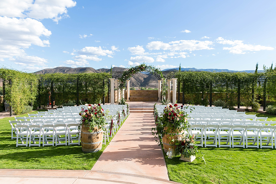  white wooden chairs and colorful florals with vineyards in the background