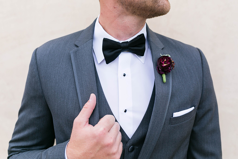  the groom in a charcoal tuxedo with a black bow tie