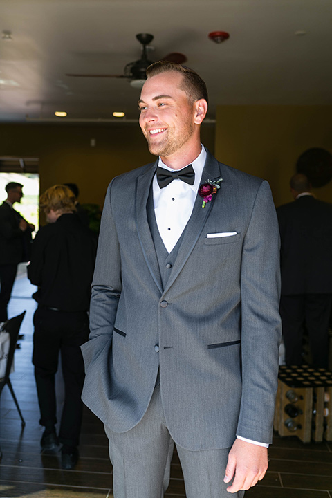  the groom in a charcoal tuxedo with a black bow tie