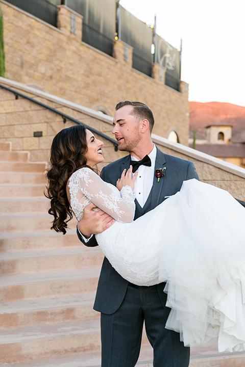 bride in a white lace gown with a full skirt and long lace sleeves and her hair in a finger wave and the groom in a charcoal tuxedo with a black bow tie 