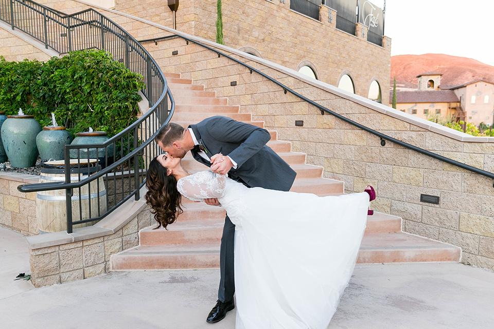 bride in a white lace gown with a full skirt and long lace sleeves and her hair in a finger wave and the groom in a charcoal tuxedo with a black bow tie