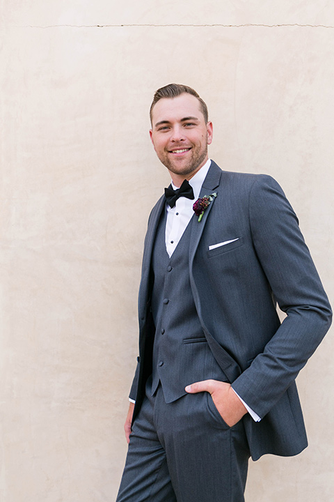  the groom in a charcoal tuxedo with a black bow tie 