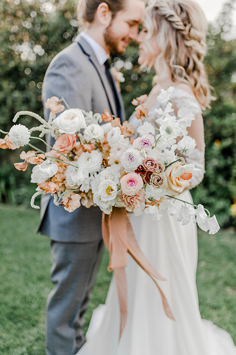 bride in a white gown with an illusion neckline hair in a loose curl, groom in a grey suit with a black trim and long black tie