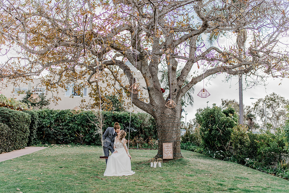 bride in a white lace gown with an illusion neckline and the groom in a grey suit with black trim and black long tie