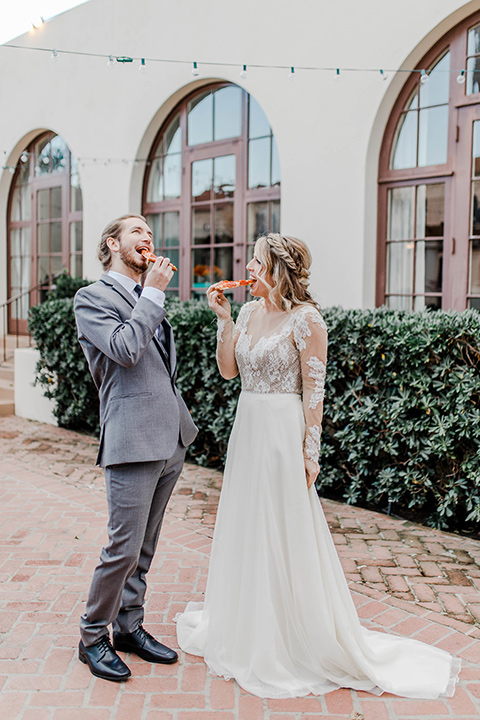 bride in a white gown with an illusion neckline hair in a loose curl, groom in a grey suit with a black trim and long black tie