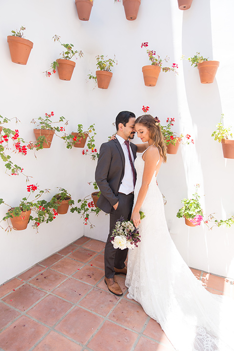 bride in a white gown with thin straps and lace detailing and the groom in a grey suit with a red long tie