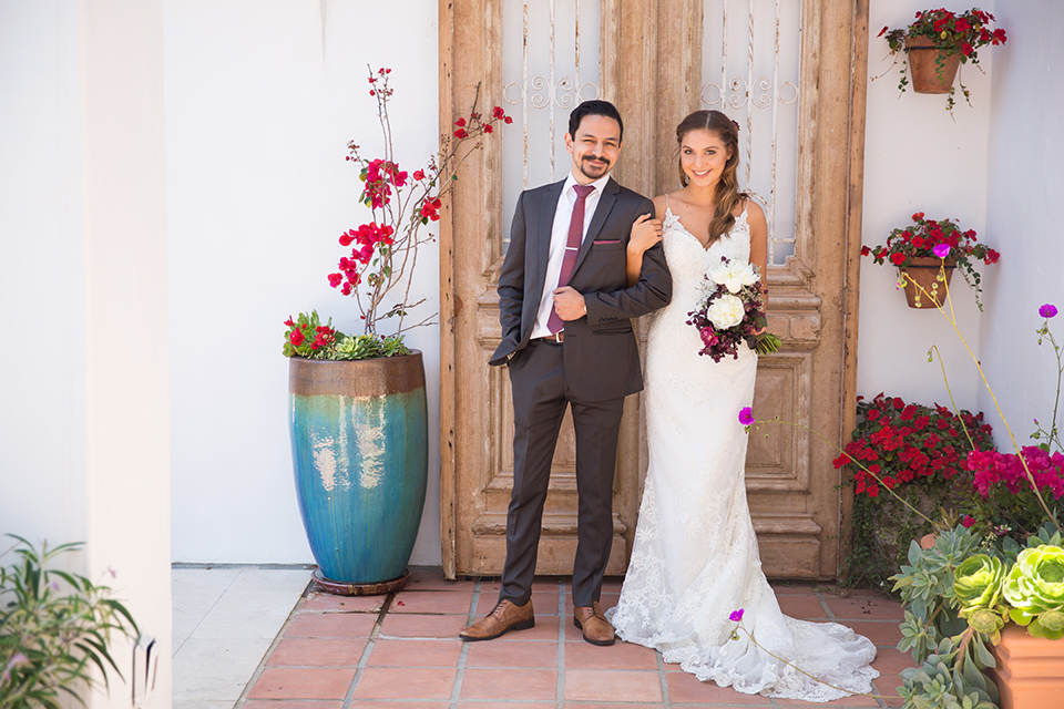 groom in a grey suit with a red long tie and the bride in a white lace gown with thin straps