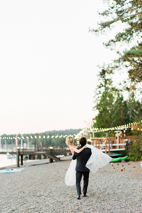 Lake Tahoe wedding groom carrying bride in a strapless ballgown with a strapless ballgown with a tulle skirt and the groom in a navy shawl lapel tuxedo 